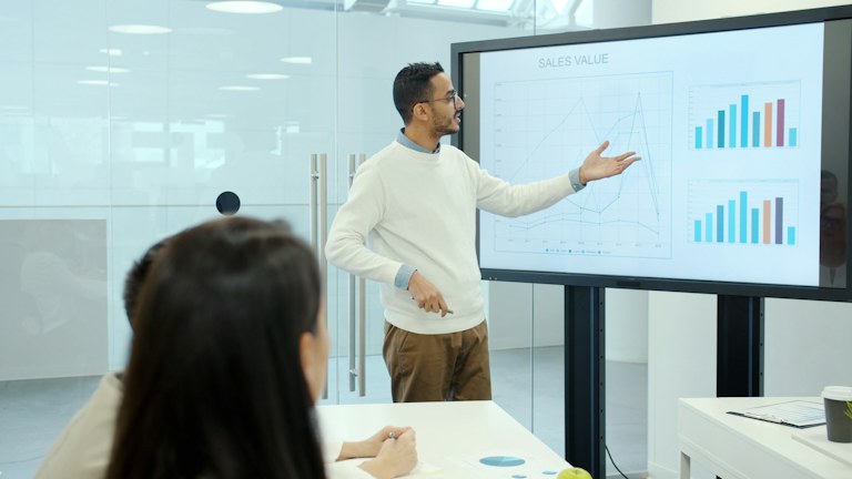 Man presenting charts on a large screen